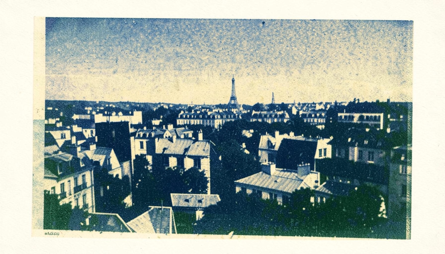 Risograph print of Parisian rooftops and a distant landmark, navy blue and warm cream, two-ink duotone with soft texture