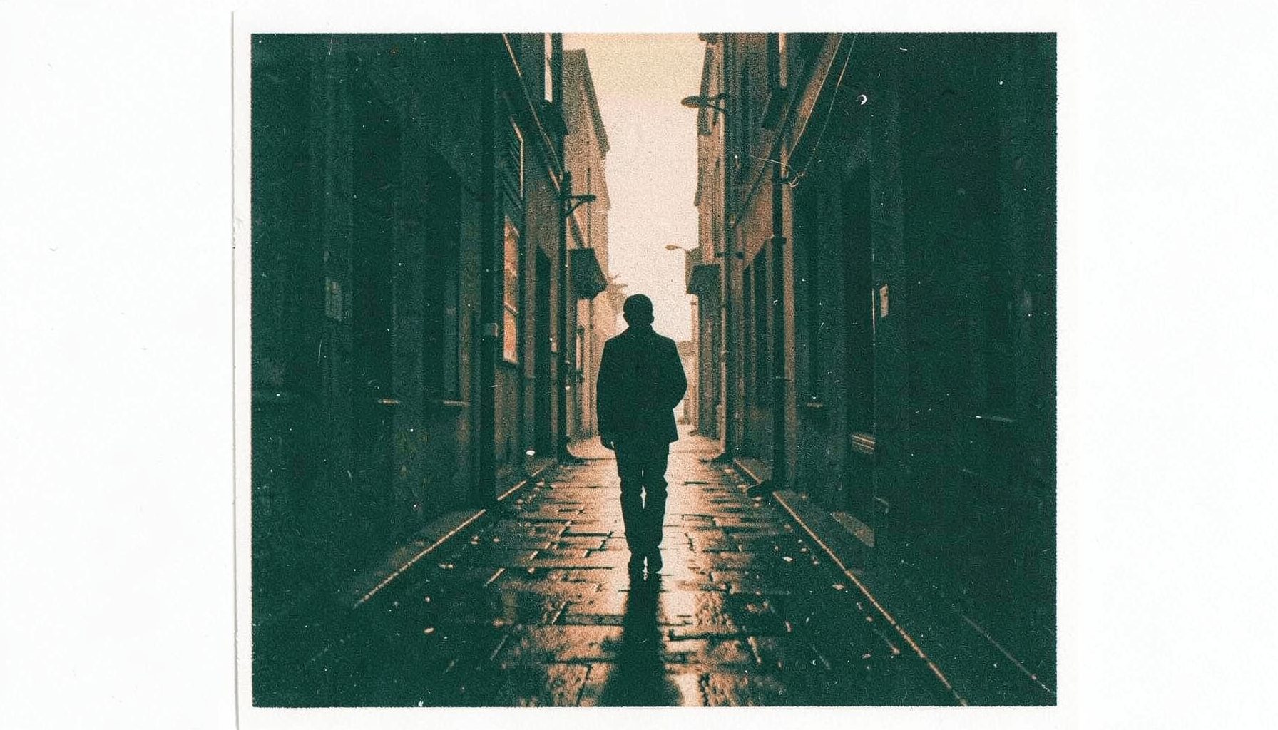 A risograph print in charcoal and burnt sienna showing a lone figure walking down a narrow alley at dusk, with neon reflections on wet pavement.